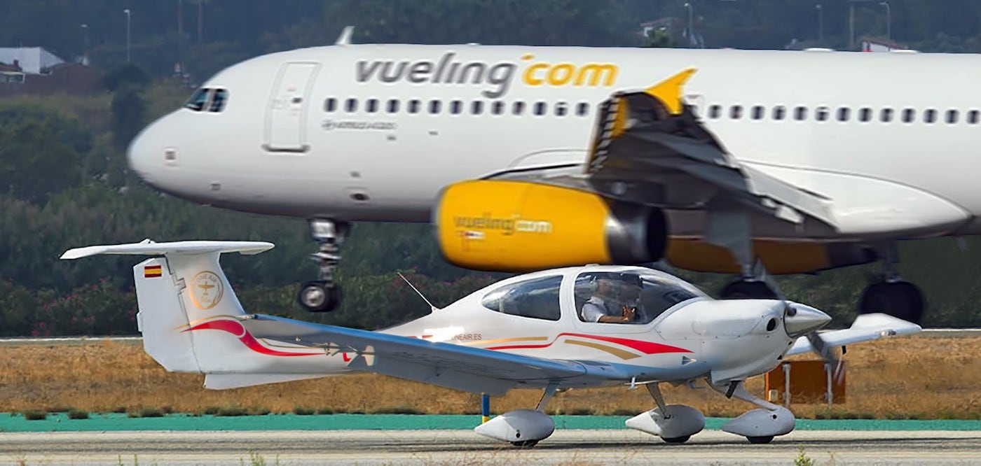 one airs diamond da42 at malagas international airport with a vueling plane in the background