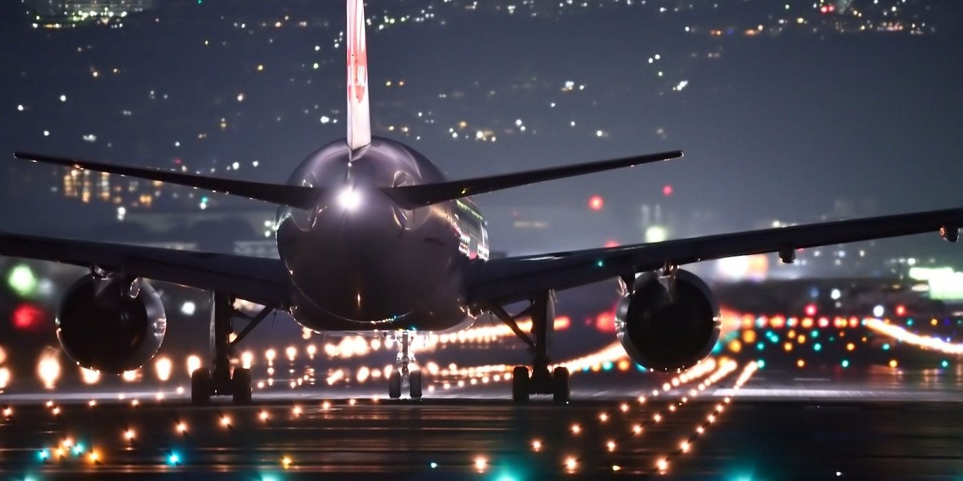 rear view of airplane moving forward runway illuminated at night