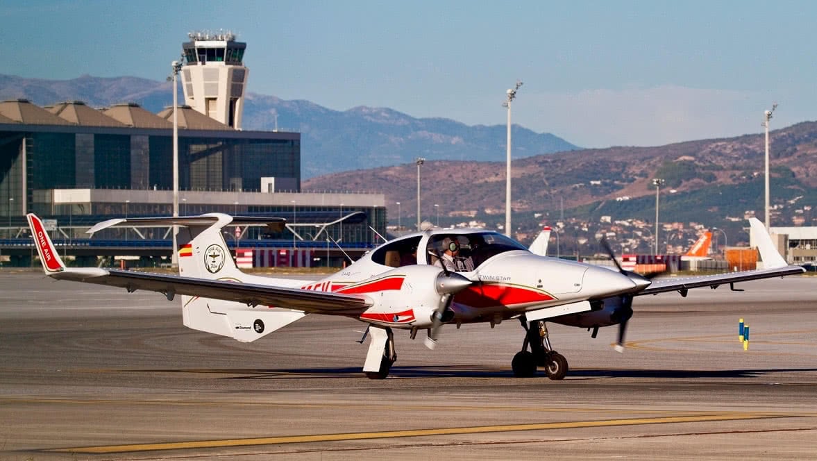 a oneairs diamond da42 al malagas international airport with control tower in the background