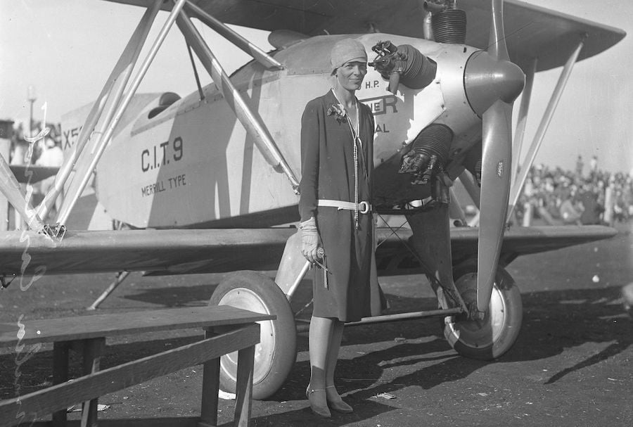 Amelia Earhart posing next to an aeroplane